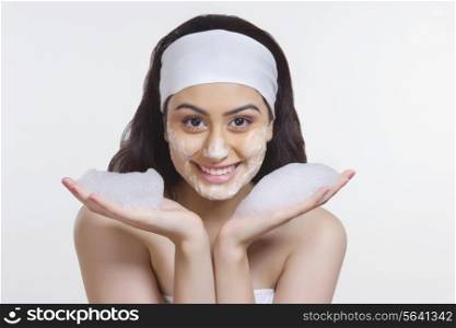 Portrait of happy woman washing face with soap against white background