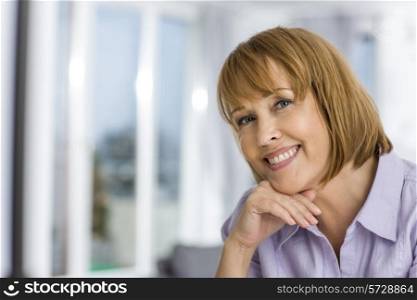 Portrait of happy woman with hand on chin at home