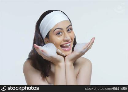 Portrait of happy woman with soap sud against gray background