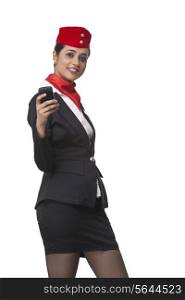 Portrait of happy young airhostess text messaging on cell phone isolated over white background