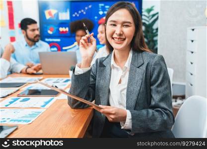 Portrait of happy young asian businesswoman with group of office worker on meeting with screen display business dashboard in background. Confident office lady at team meeting. Concord. Portrait of happy young asian businesswoman with in office meeting. Concord
