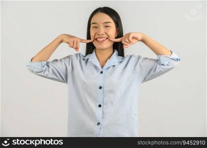 Portrait of Happy young asian woman in blue shirt smiling finger cheek isolated on white background. Expression and lifestyle concept.