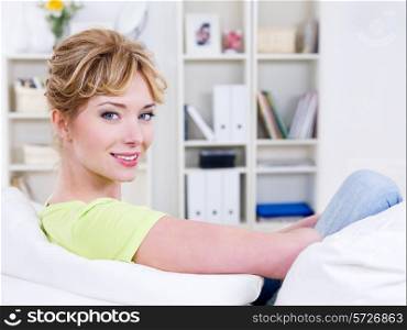 Portrait of happy young beautiful woman sitting on the sofa