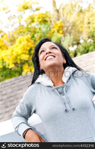 Portrait of happy young black woman looking up outdoors in fall