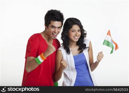 Portrait of happy young boy cheering with female friend holding Indian flag over white background