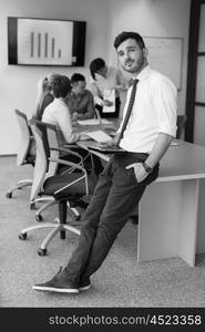 Portrait of happy young businessman with tablet computer office. People group on team meeting in background