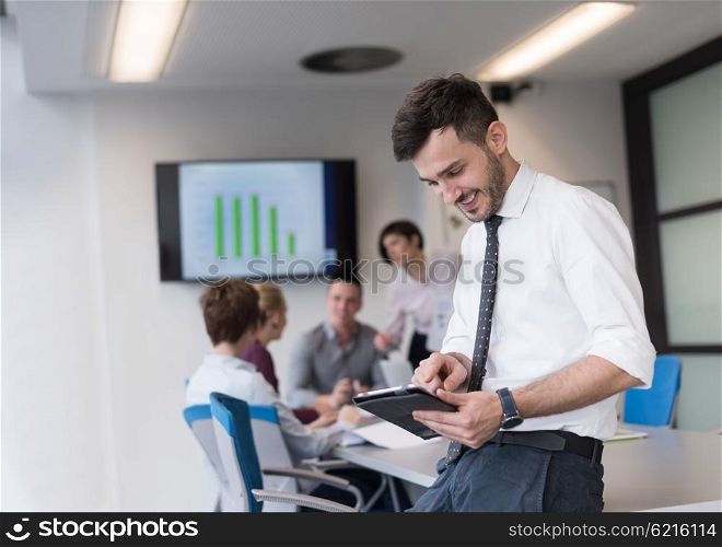 Portrait of happy young businessman with tablet computer office. People group on team meeting in background