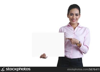 Portrait of happy young businesswoman pointing at blank board over white background