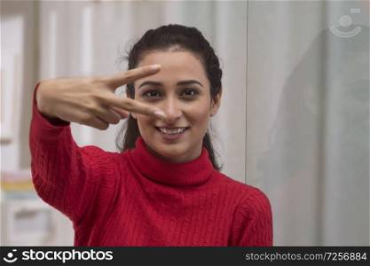 Portrait of happy young businesswoman showing victory sign