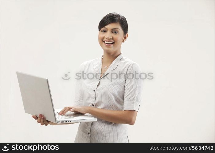 Portrait of happy young businesswoman working on laptop