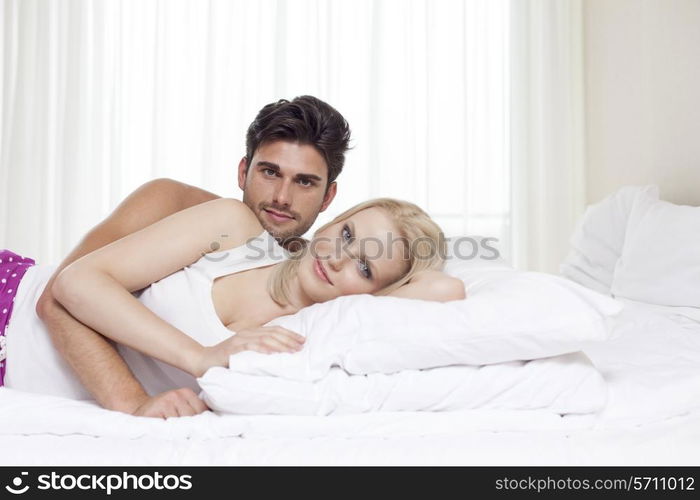 Portrait of happy young couple lying in bed