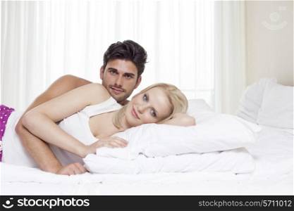 Portrait of happy young couple lying in bed