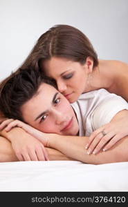 Portrait of happy young couple lying in bed and smiling isolated on light background