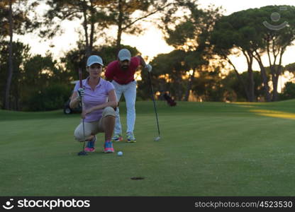 portrait of happy young couple on golf course with beautiful sunset in background