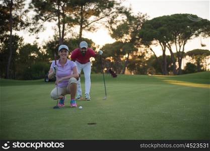 portrait of happy young couple on golf course with beautiful sunset in background