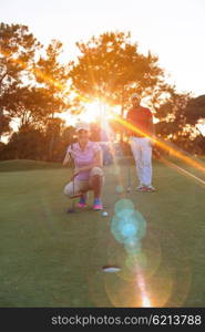 portrait of happy young couple on golf course with beautiful sunset in background