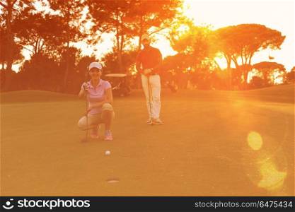 portrait of happy young couple on golf course with beautiful sunset in background. couple on golf course at sunset