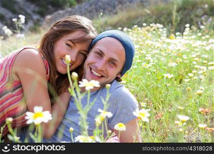 Portrait of happy young couple reclining in field of wild flowers