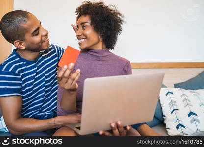 Portrait of happy young couple shopping online with credit card and laptop at home. Shop online and relationship concept.