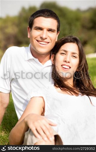 Portrait of Happy young couple sitting and smiling in the park