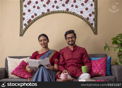 Portrait of happy young couple sitting together on sofa at home