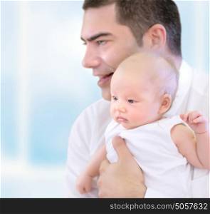 Portrait of happy young father holding on hands cute little precious baby, spending time together at home, loving young family