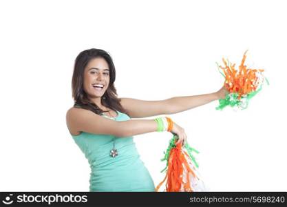 Portrait of happy young female holding out tricolor pom poms over white background
