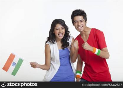Portrait of happy young girl holding Indian flag while standing with friend over white background