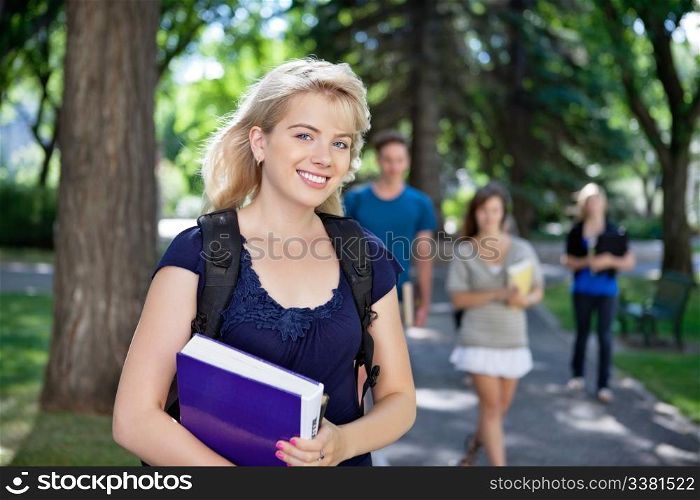 Portrait of happy young girl smiling while her classmates walking in background