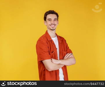 Portrait of happy young handsome man standing with crossed arms with isolated on studio yellow background. Male smiling and looking at camera.