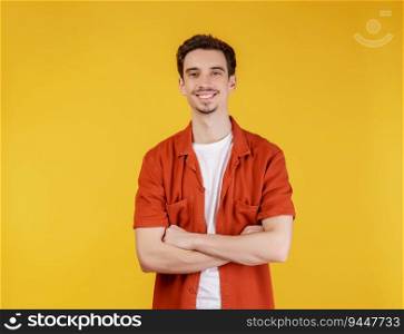 Portrait of happy young handsome man standing with crossed arms with isolated on studio yellow background. Ma≤smiling and looking at camera.