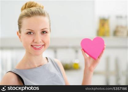 Portrait of happy young housewife showing decorative heart