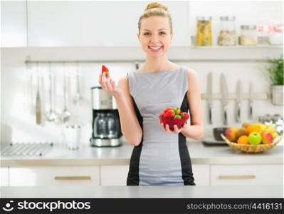 Portrait of happy young housewife with plate of strawberries in modern kitchen