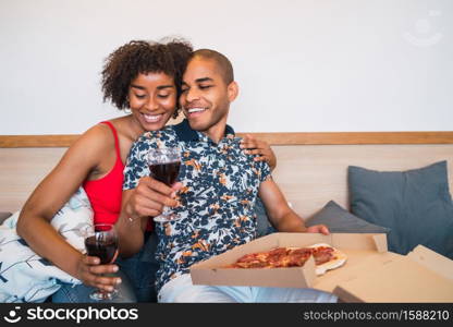 Portrait of happy young latin couple having dinner together and drinking wine at their home. Lifestyle and relationship concept.