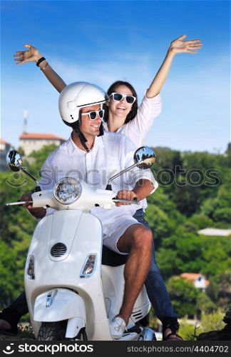 Portrait of happy young love couple on scooter enjoying themselves in a park at summer time