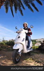 Portrait of happy young love couple on scooter enjoying themselves in a park at summer time