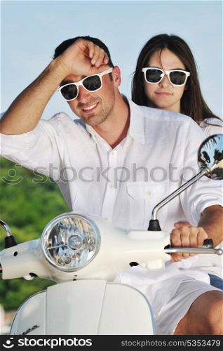 Portrait of happy young love couple on scooter enjoying themselves in a park at summer time