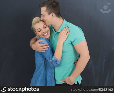 portrait of happy young loving couple in front of gray chalkboard