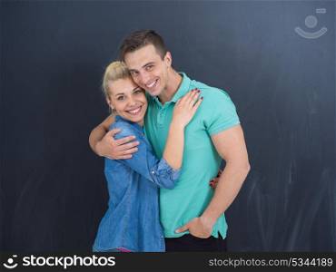 portrait of happy young loving couple in front of gray chalkboard