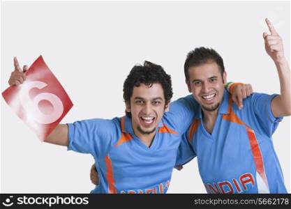 Portrait of happy young male friends Indian cricket team jerseys standing together arm around over white background