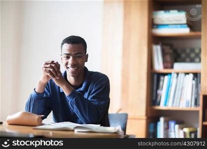 Portrait of happy young male high school student sitting at desk