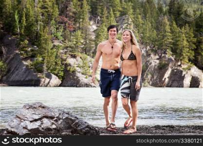 Portrait of happy young man and woman walking by the lake