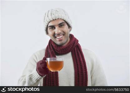 Portrait of happy young man drinking black tea over colored background
