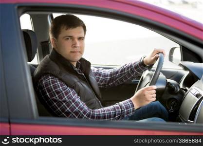 Portrait of happy young man driving small car
