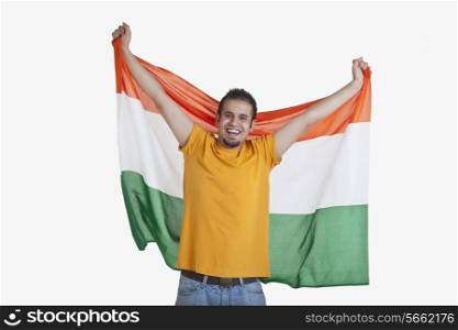 Portrait of happy young man in casual wear holding out Indian flag over white background