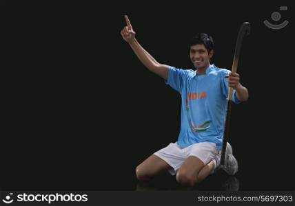 Portrait of happy young man in sportswear holding hockey stick while celebrating success