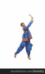 Portrait of happy young man in traditional clothes performing Dandiya Raas against white background