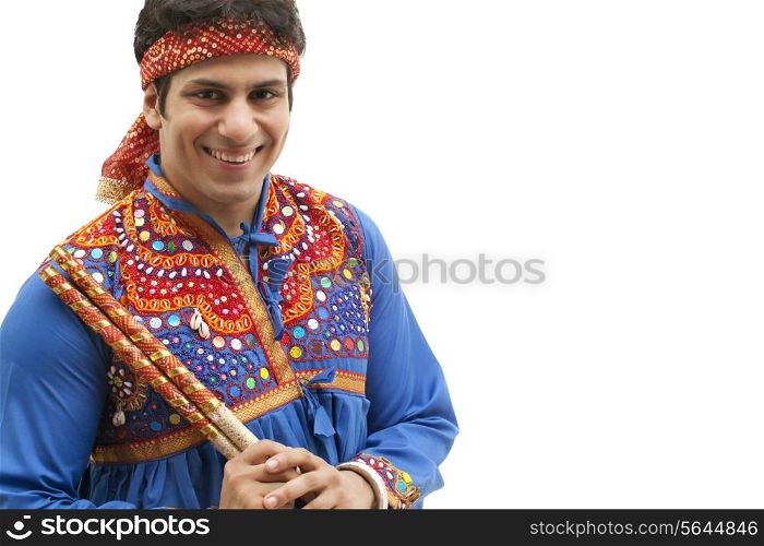 Portrait of happy young man in traditional wear holding dandiya isolated over white background
