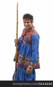 Portrait of happy young man in traditional wear holding stick against white background