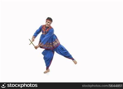 Portrait of happy young man in traditional wear performing Dandiya Rass over white background